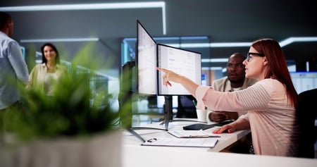 Two Office Personnel Working Together at a Desk on a Computer